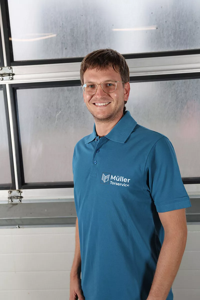 Frank Müller, Inhaber von Müller Torservice, im Firmen-Polo vor einer Industrie-Toranlage